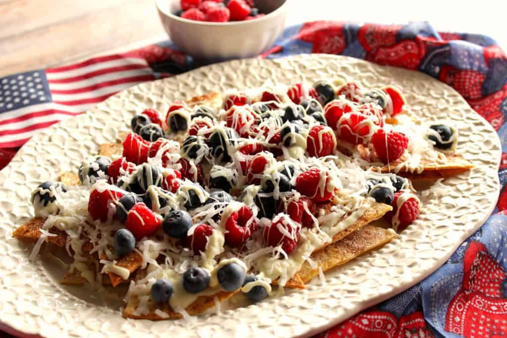 Platter of dessert nachos with raspberries, blueberries, and white chocolate.