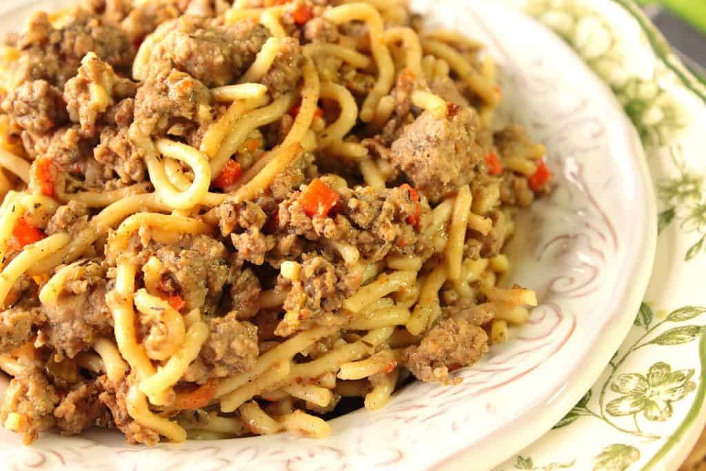 An offset photo of a bowl filled with Turkey Bolognese over spaghetti with carrots and celery.