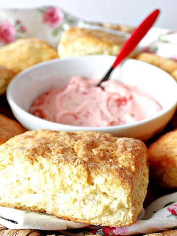 A pretty basket with a pink rose napkin filled with Cream Cheese Biscuits with Strawberry Butter in the center.