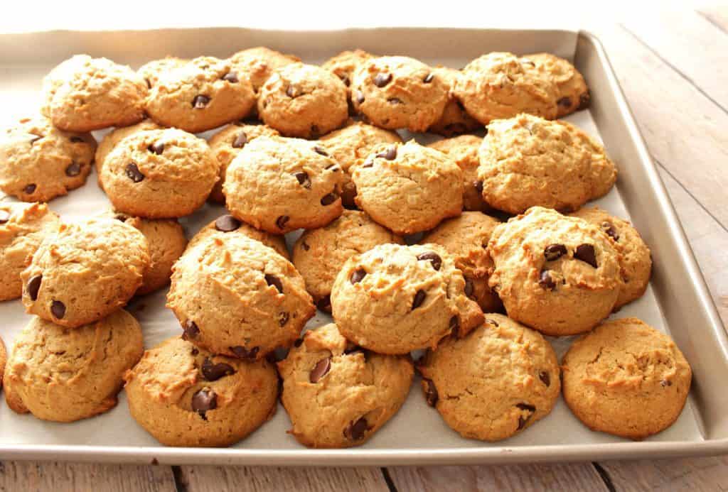 A horizontal photo of a baking sheet piled high with peanut butter chocolate chip banana cookies.