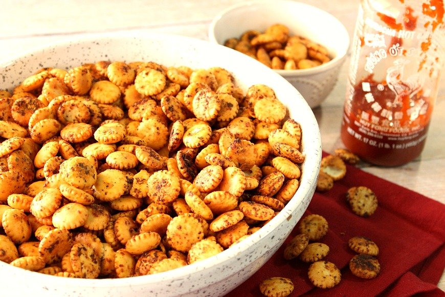 A white bowl filled with Sriracha Firecracker Snackers along with a red napkin.