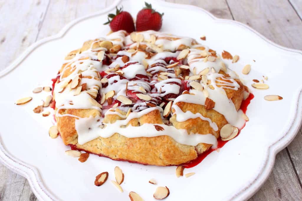 Rustic Strawberry Crostata on a pretty white plate with slivered almonds as garnish.