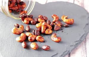 A bunch of Browned Butter Roasted Nuts spilled out over a black slate heart tile.