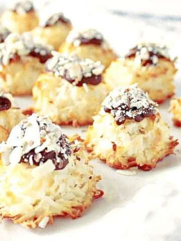 A white tray filled with Almond Joy Coconut Macaroons with chocolate and almonds on top.