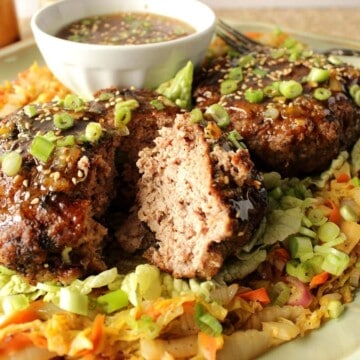 A plate of crispy duck patties with Asian cabbage and orange dipping sauce.