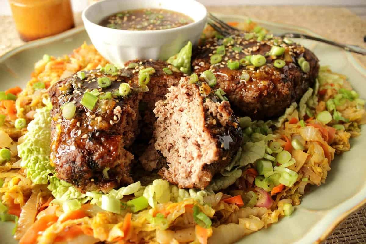 A plate of crispy duck patties with Asian cabbage and orange dipping sauce.
