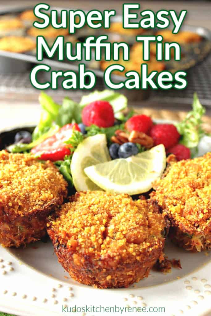 muffin tin crab cakes on a white plate with a salad and lemon wedges in the background.