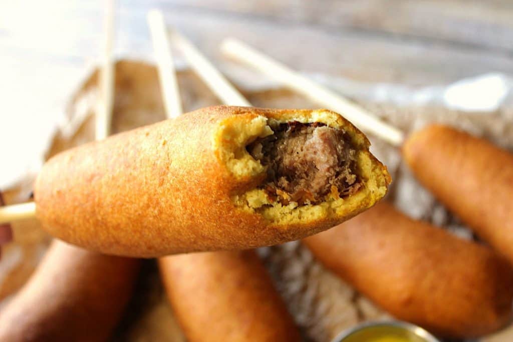 Closeup photo of Beer batter bratwurst with a bite taken out.