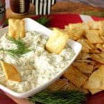 Cucumber Dill Dip in a white bowl with chips on the side and fresh dill on top.