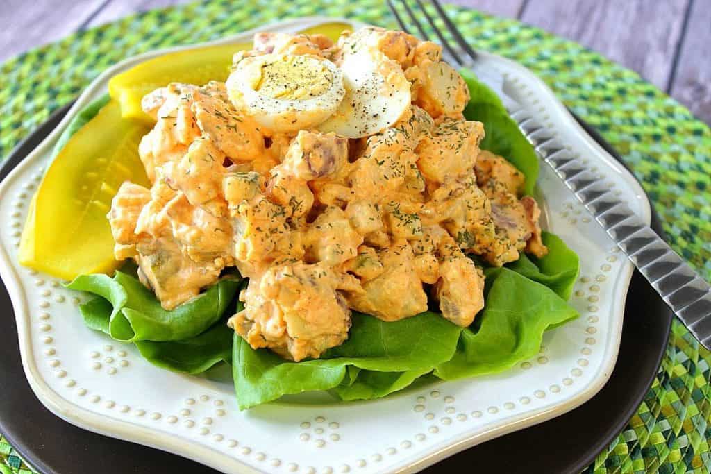 Creamy Potato Salad on a bed of lettuce on a white plate.