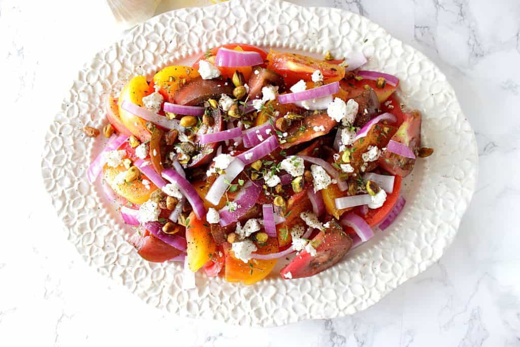 Colorful heirloom tomatoes take their rightful place in the spotlight in this delicious and flavorful Heirloom Tomato Salad with Garlic Lemon Infused Olive Oil. - Kudos Kitchen by Renee - www.kudoskitchenbyrenee.com Heirloom tomato salad