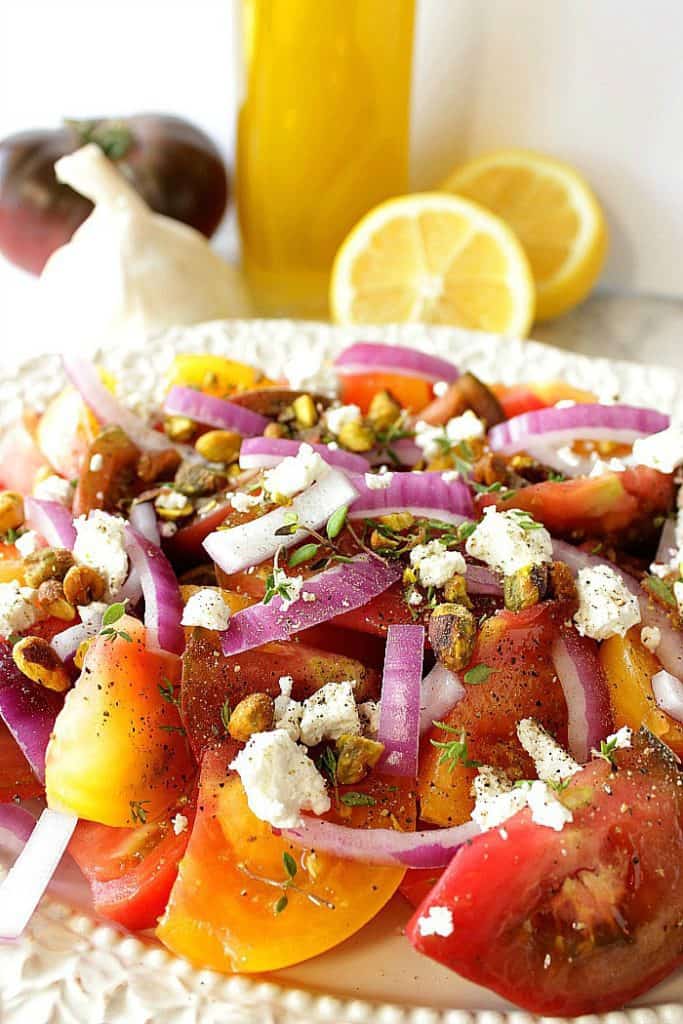 Heirloom tomato salad with goat cheese and pistachios with lemons and garlic in the background