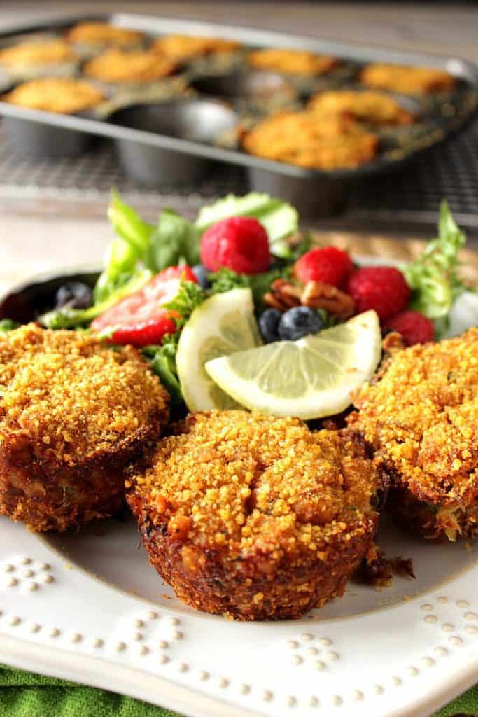 Meaty Cornflake Muffin Tip Crab Cakes on a white plate with a salad and a muffin tin in the background.