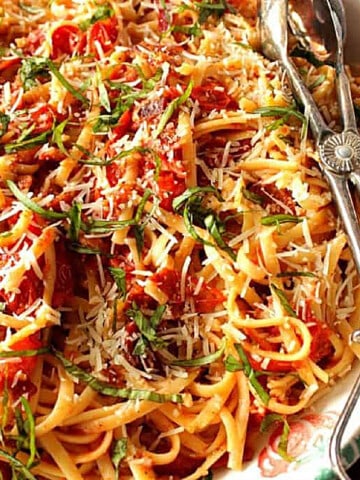 A large bowl filled with Roasted Tomato Bacon Linguine along with serving tongs.