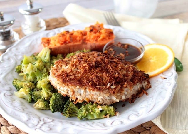 A colorful horizontal photo of a coconut crusted tuna steak on a plate with broccoli, and a sweet potato.