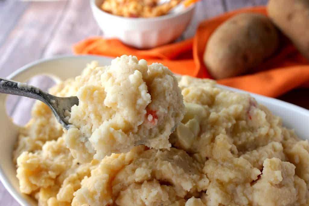 A closeup of a spoon holding a serving of Pimento Cheese Mashed Potatoes