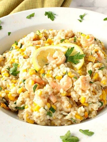 Creamy Risotto with Sweet Corn and Shrimp in a white bowl topped with parsley.