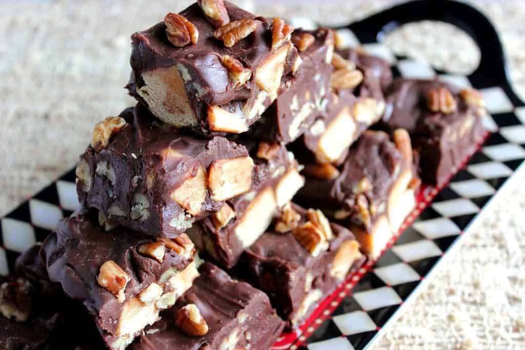 A horizontal closeup photo of a stack of turtle fudge on a harlequin plate.