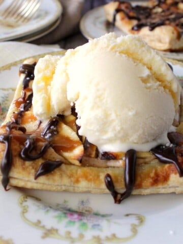 A Puff Pastry Apple Square on a china plate with a scoop of vanilla ice cream on top.