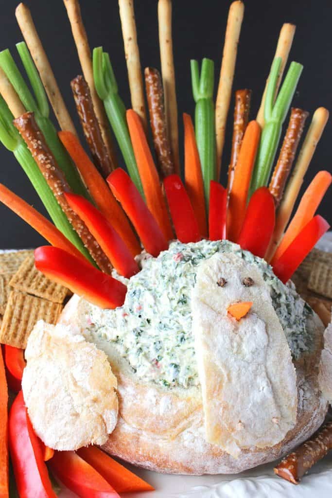 Closeup vertical image of a turkey bread bowl appetizer with colorful dipper "feathers"