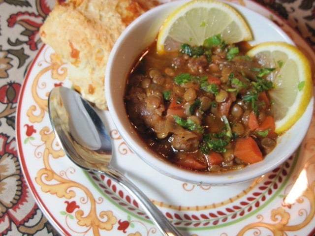 Red Lentil Soup in a bowl with lemon slices and a spoon.