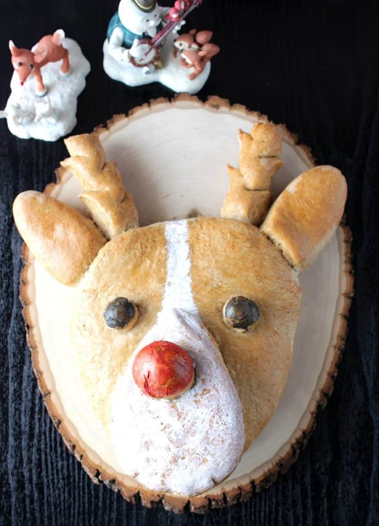 Overhead vertical image of whole wheat Rudolph Bread on a black background with a wooden board.