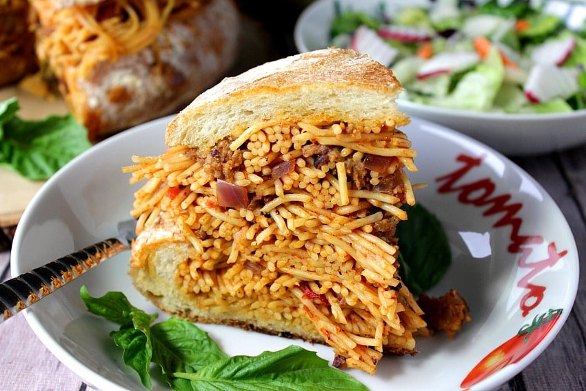 A slice of Spaghetti Stuffed Garlic Bread in a bowl with fresh basil.