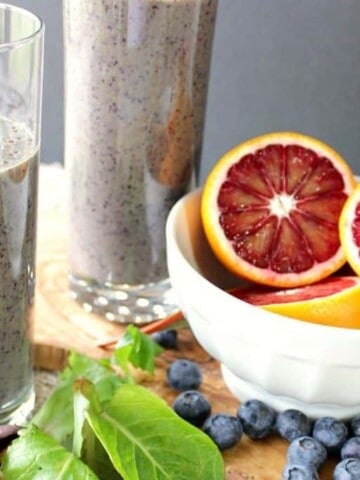 Two glasses filled with Blood Orange Breakfast Smoothies along with spinach and blueberries