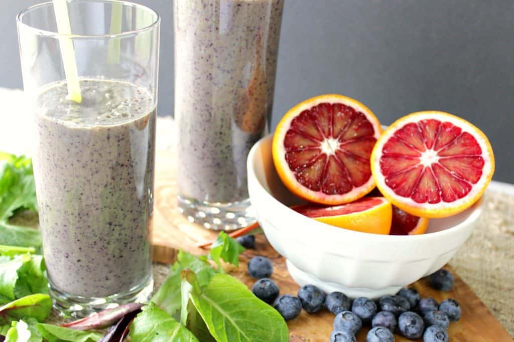 2 blood orange blueberry breakfast smoothies with a bowl of blood oranges, blueberries and lettuces