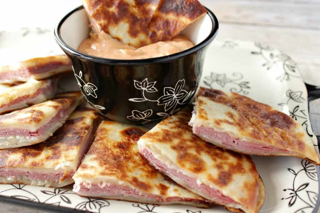 A horizontal photo of Corned Beef Reuben Quesadillas with 1000 Islands dipping sauce.