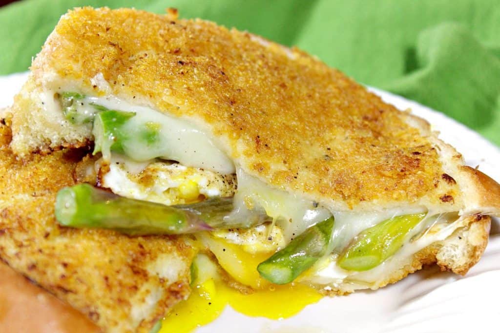 Grilled Cheese Breakfast Sandwich Closeup picture of a melted grilled cheese sandwich with asparagus and a runny egg.