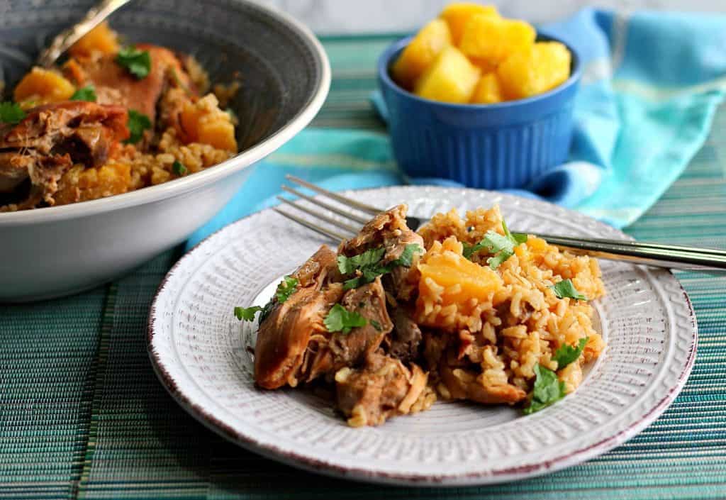 A serving of Slow Cooker Hawaiian Pineapple Chicken Thighs on a plate the pineapple and rice.