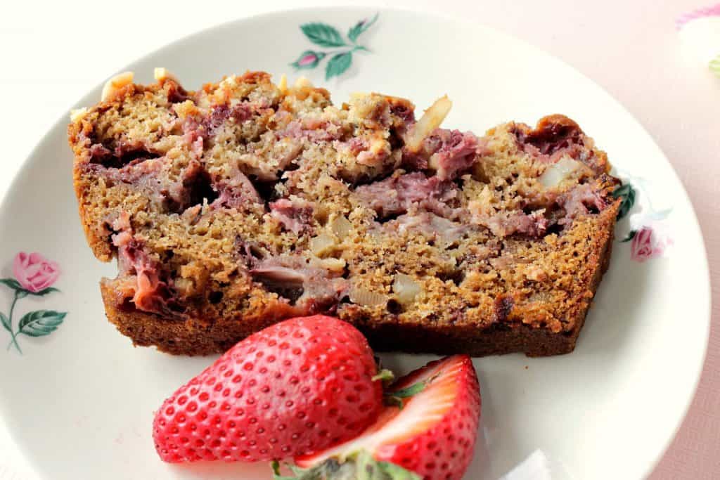 A slice of strawberry banana quick bread on a cute plate with little rosebuds.