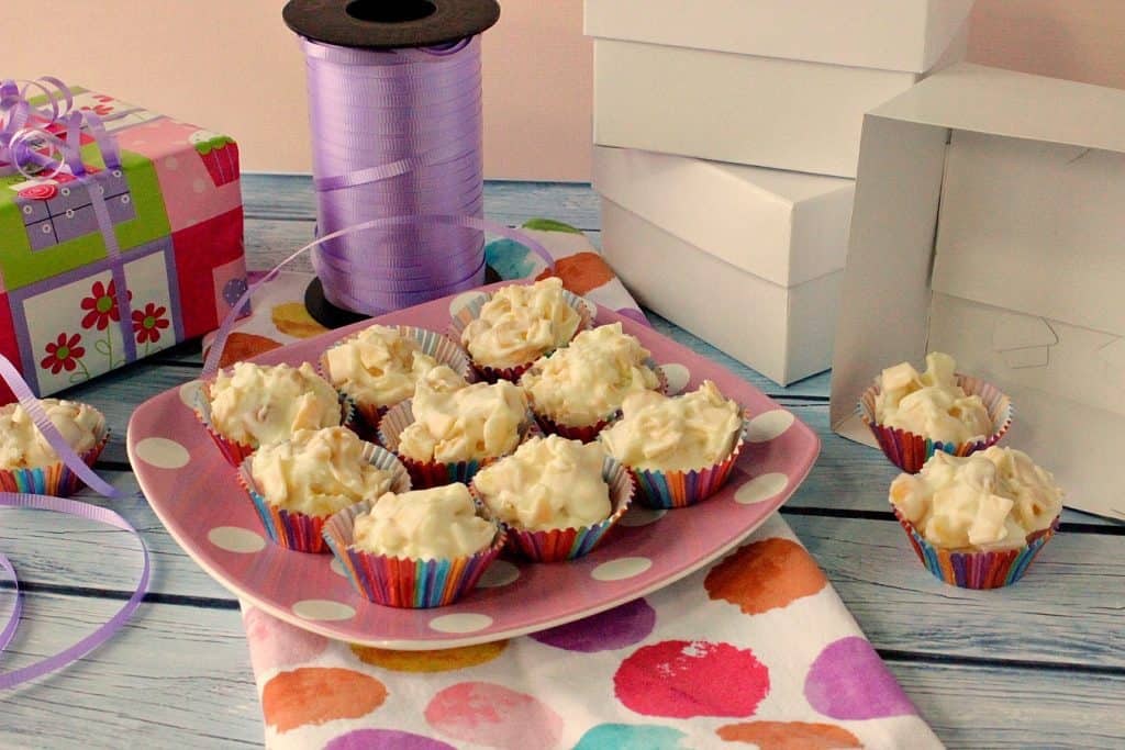 Candy boxes and ribbon surrounding a plate of Tropical White Chocolate Candy Bites.