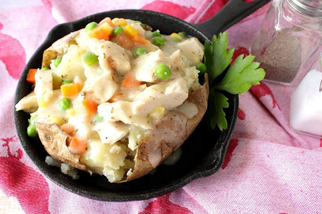 A chicken pot potato in a small skillet with parsley and a slat and pepper shaker in the background.