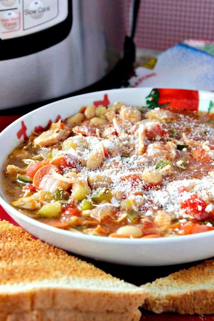 A vertical closeup photo of a bowl of Italian pepperoni soup sprinkled with Parmesan cheese with an instant pot in the background. Comfort food soups, stews, and chowders recipe roundup.