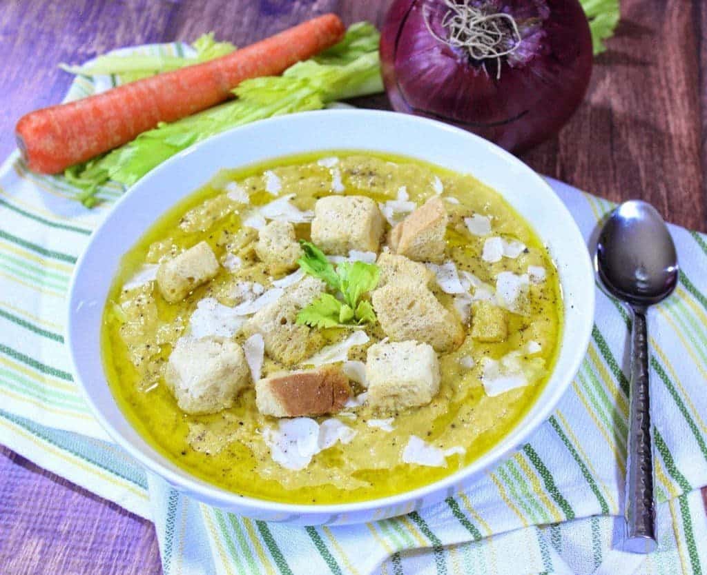 Roasted Cream of Celery Soup in a white bowl with croutons and a spoon on the side.