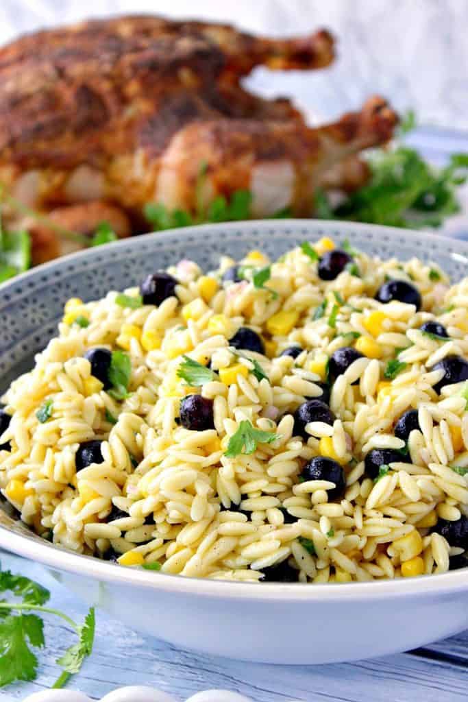 An Orzo Pasta Salad in a blue bowl with corn can blueberries.