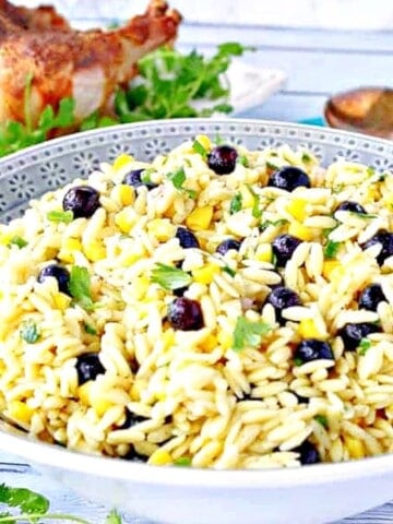 A blue bowl filled with chilled Orzo Pasta Salad with Corn and Blueberries.