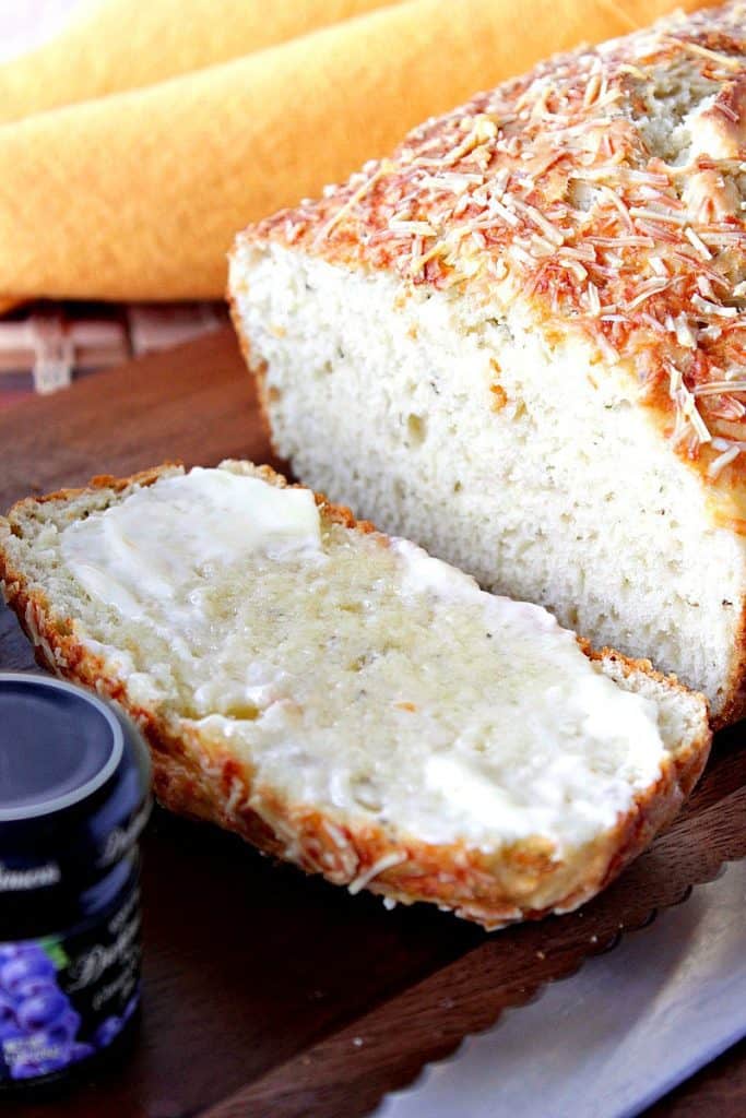 Closeup photo of a slice of Herb Parmesan Quick Bread with butter.