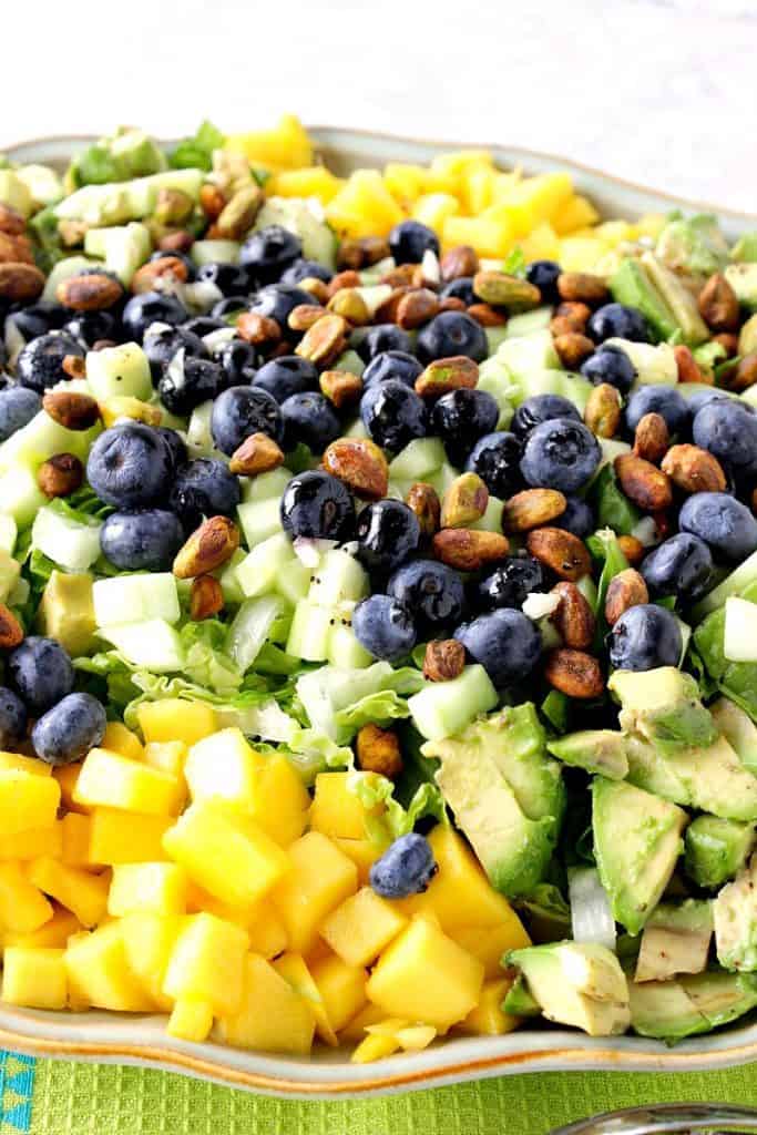 Closeup photo of an avocado mango salad with blueberries and pistachios.