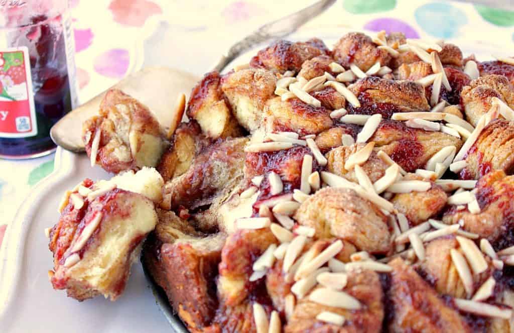 A loaf of Raspberry Spiced Monkey Bread on a platter with two pieces taken out.