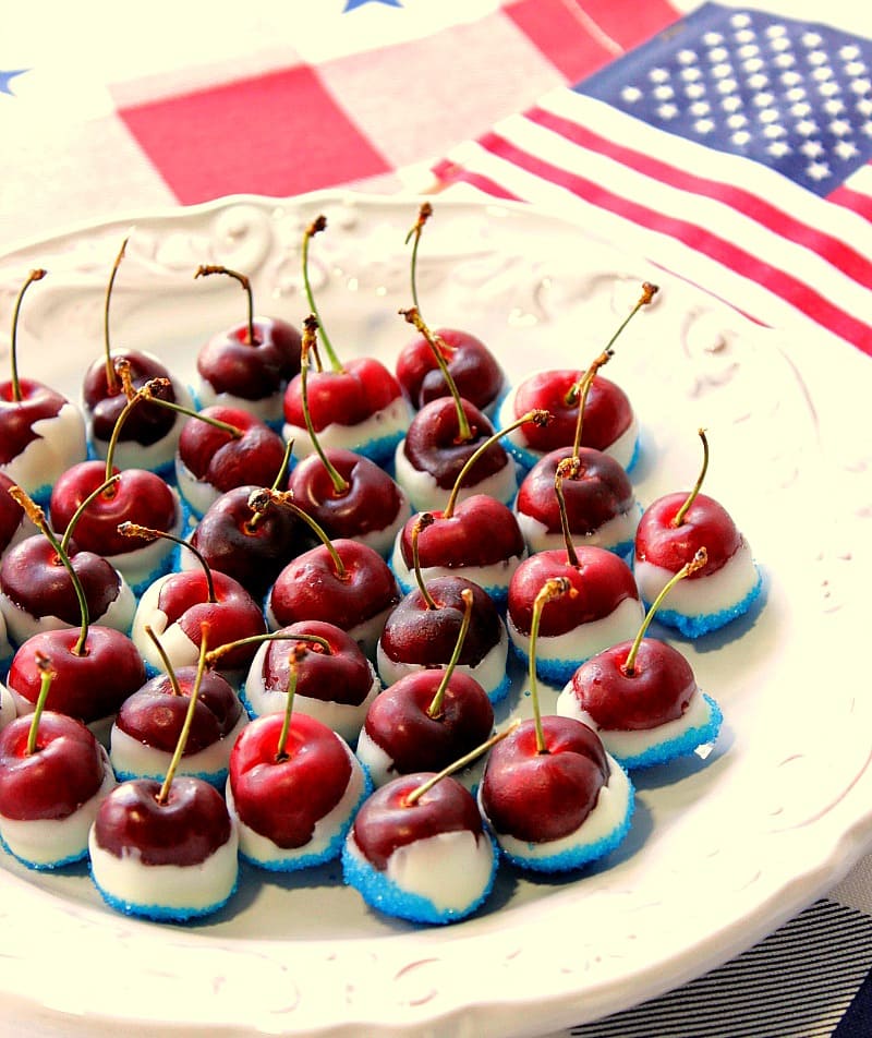 Red White & Blue Sugared Cherries on an oval white plate with an American flag in the background
