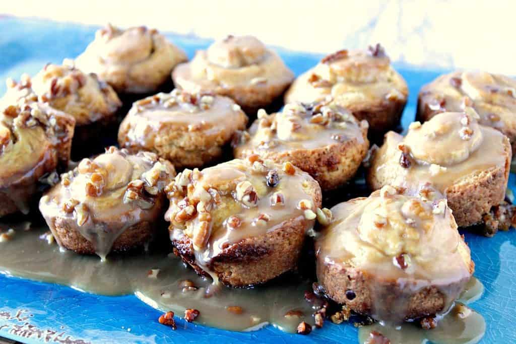A plate full of sweet rolls topped with caramel and pecans.