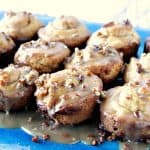 A plate full of sticky caramel sweet rolls with pecans