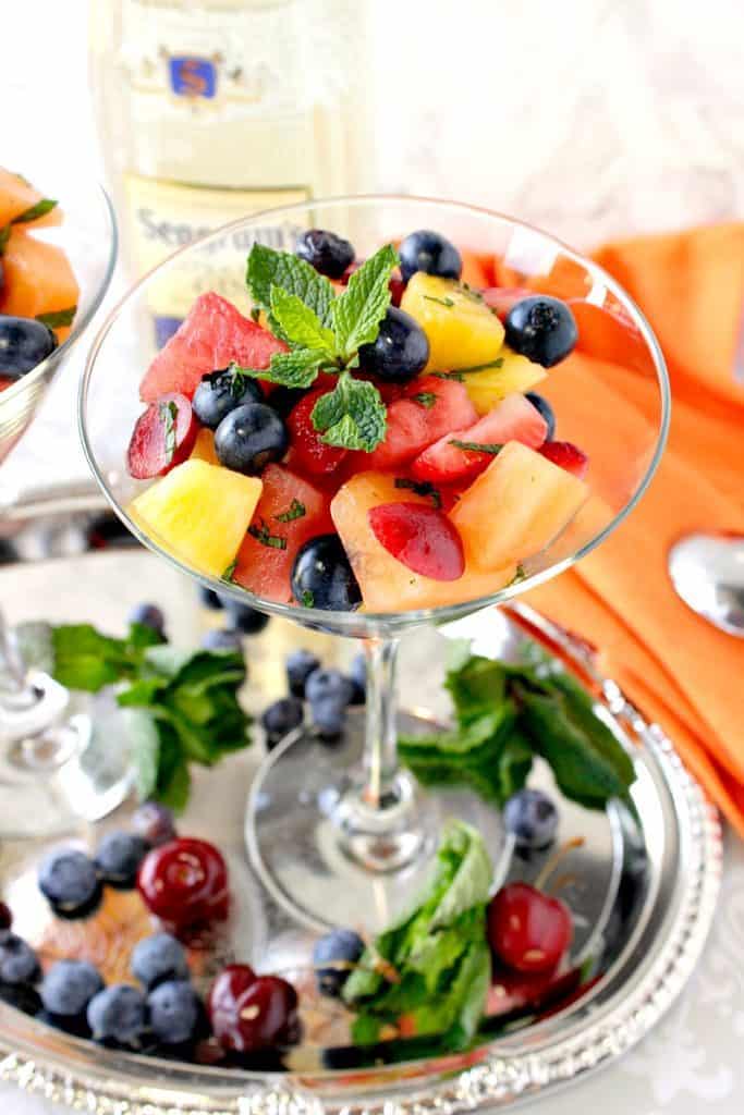 Closeup overhead photo of Boozy Fruit Cocktail with cherries, pineapple, watermelon & blueberries in a martini glass on a sliver tray.