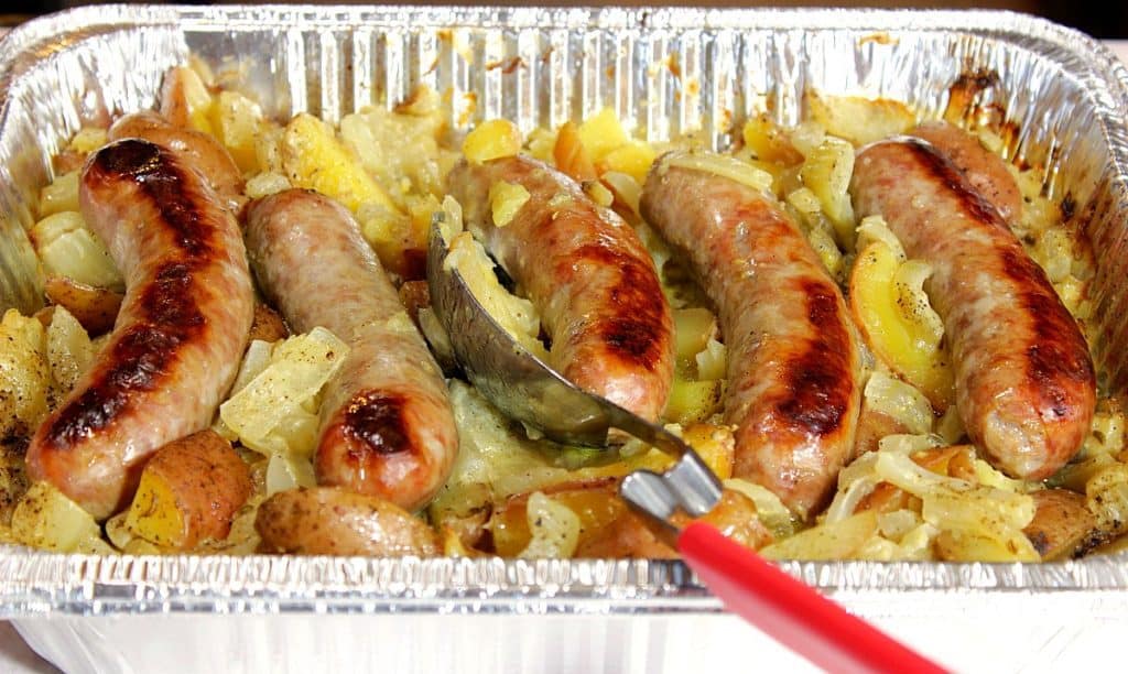 One Pan Italian Sausage Fennel & Potato Dinner in an aluminum pan with a large serving spoon.