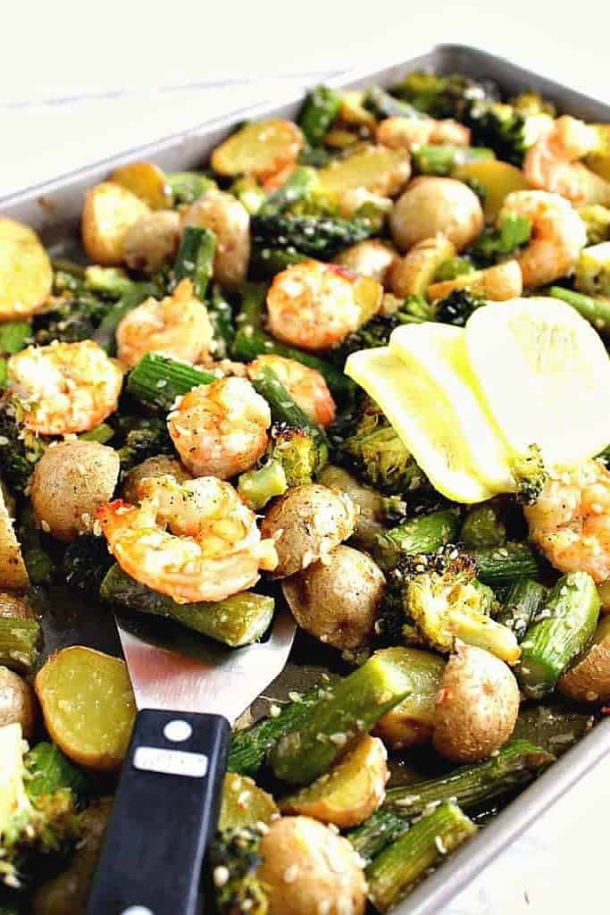 A sheet tray of shrimp, potatoes, asparagus and broccoli.