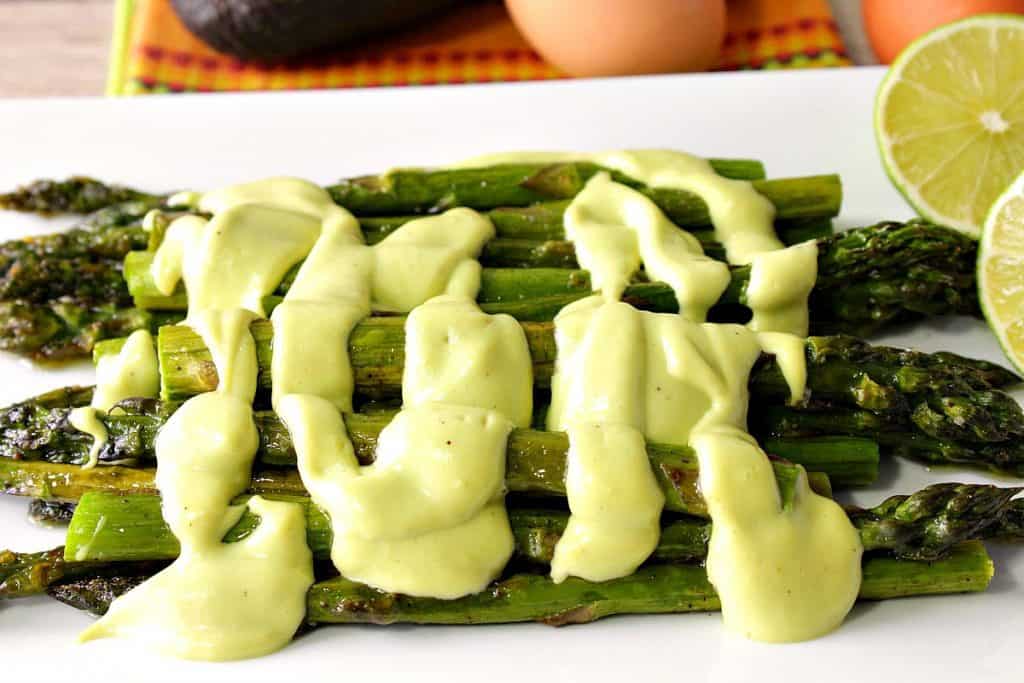 Closeup photo of avocado hollandaise sauce over oven roasted asparagus.