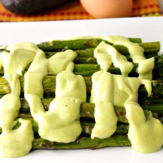 Creamy Avocado Hollandaise Sauce over Roasted Asparagus on a plate